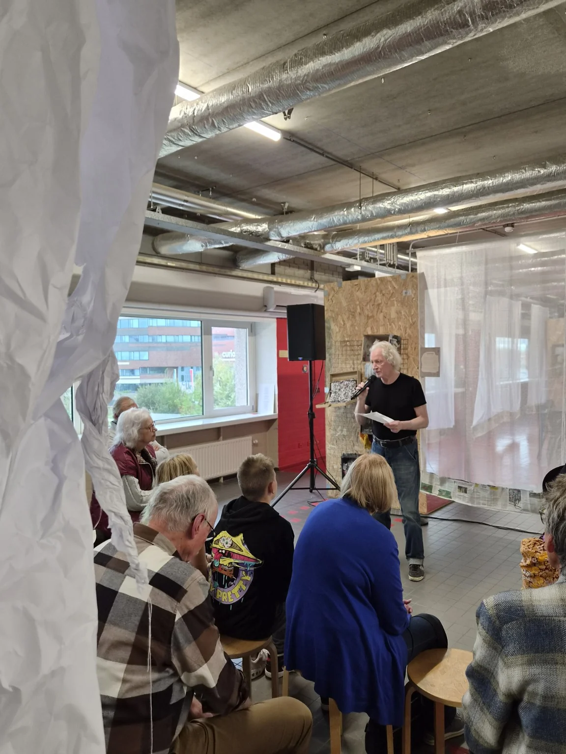 Een voordrager deelt een tekst in de tentoonstellingsruimte